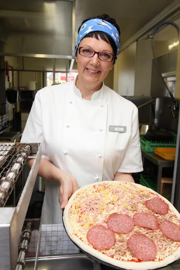 Päivi esittelee juuri koottua pizzaa Jopparin keittiössä